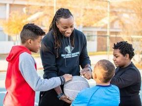 Jamal Stroud playing basketball with children.